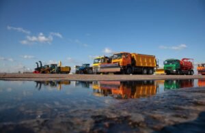 Heavy construction equipment and trucks reflecting in a large puddle under a blue sky representing robust industry digital marketing